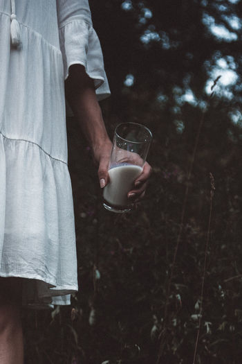 Midsection of woman holding glass of milk outdoors