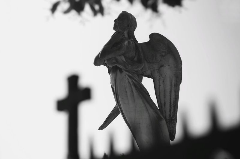 Statue of angel against sky at cemetery