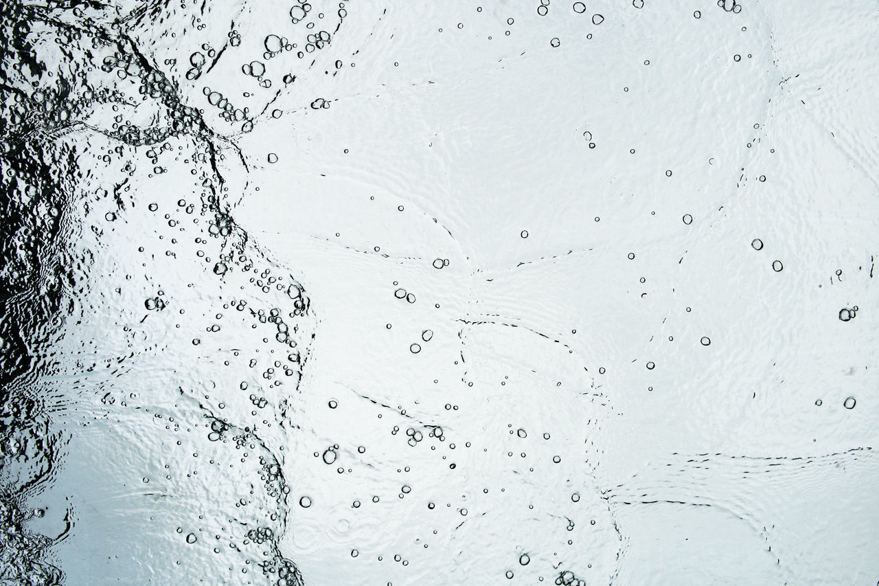 CLOSE-UP OF WATER DROPS ON GLASS AGAINST WHITE BACKGROUND