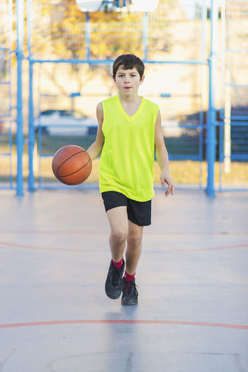 Portrait of boy playing with ball at court