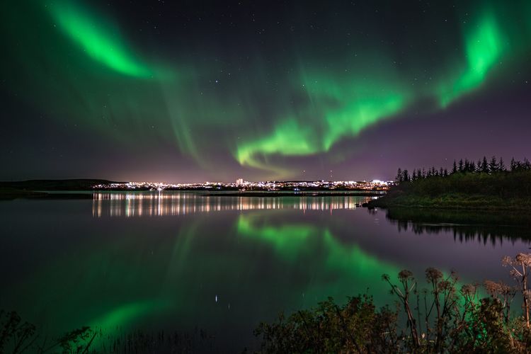 Scenic view of northern lights reflected on lake against sky at night