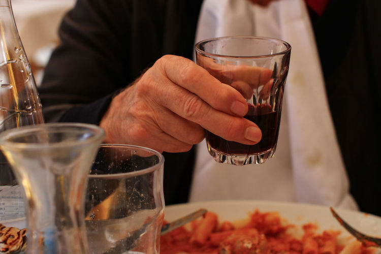 Midsection of man drinking glass on table