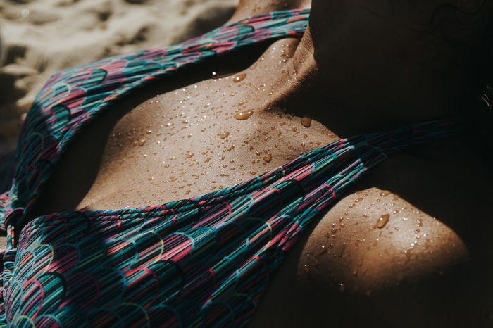 Midsection of woman in bikini at beach