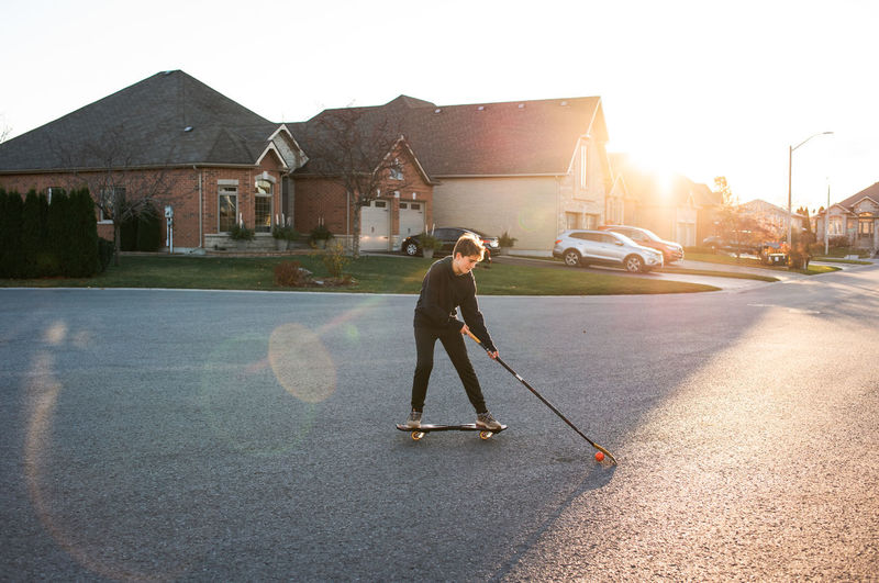 Teen boy playing street hockey on ripstick on a residential street.