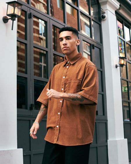 Portrait of young man standing against building