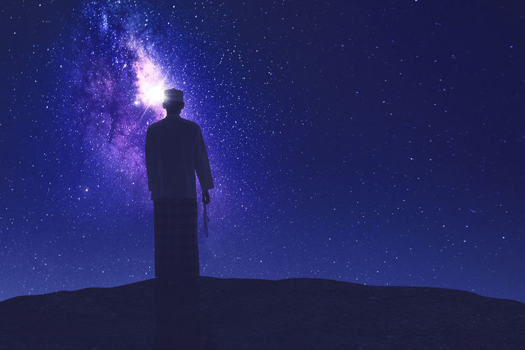 Low angle view of friends standing against sky at night