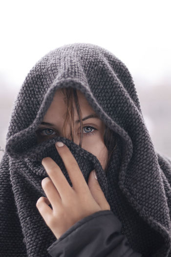Close-up portrait of a young woman wrapped in blanket