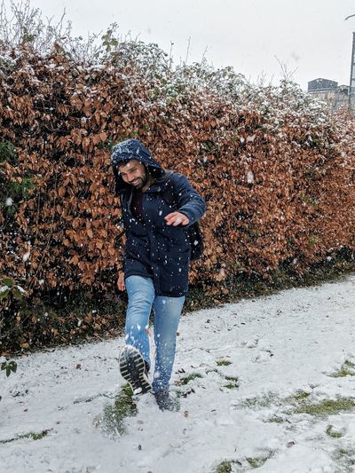 Full length of smiling man playing in snow