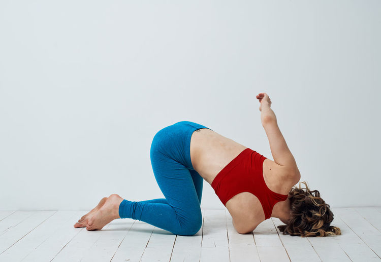 Low section of woman doing yoga against white background