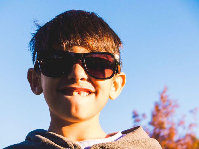 Portrait of boy wearing sunglasses against clear blue sky