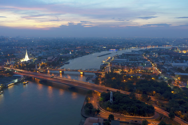 High angle view of river amidst cityscape during sunset