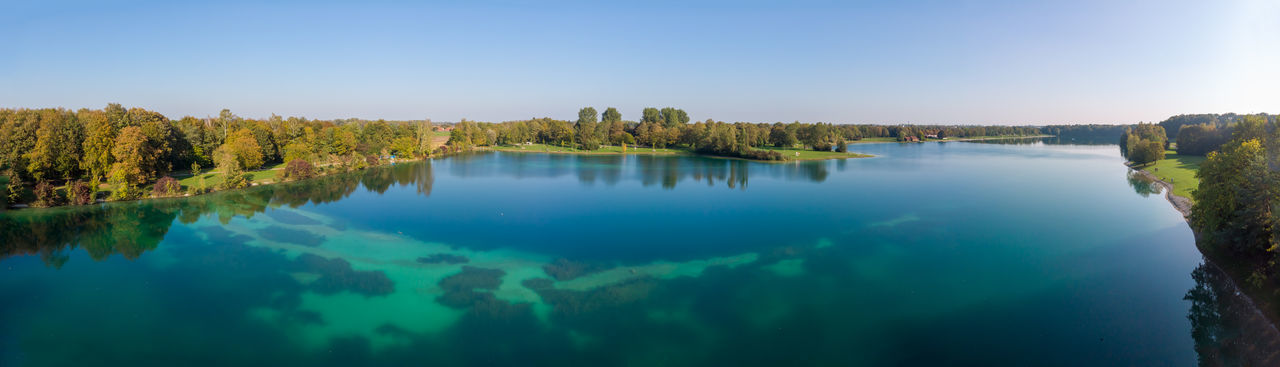 Aerial panoramia of lake karlsfeld with green and turquoise water against blue sky