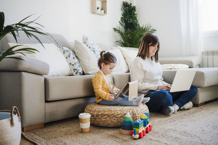 Woman and baby girl using laptop and tablet pc in living room