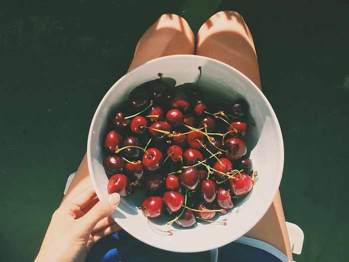 Directly above shot of woman sitting with cherry bowl