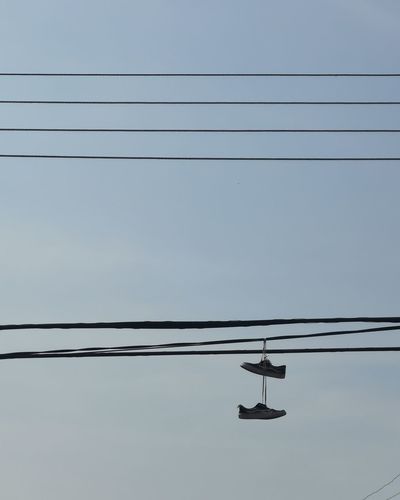 Low angle view of silhouette power lines against clear sky