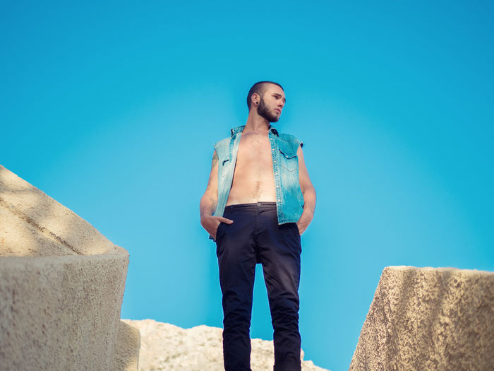 Low angle view of man standing against clear blue sky