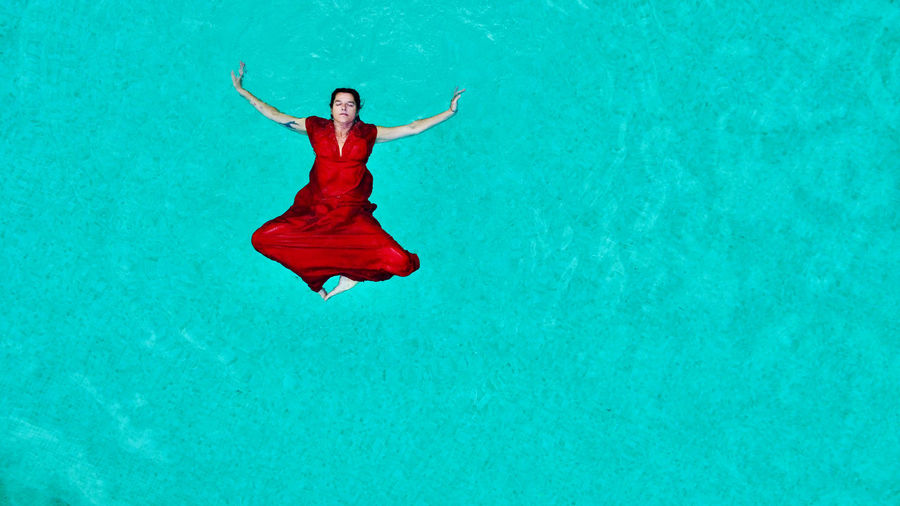 Low section of woman jumping against blue sky
