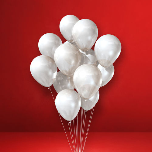Close-up of white balloons against red background