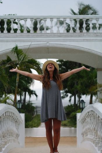 Happy woman with arms outstretched standing outdoors