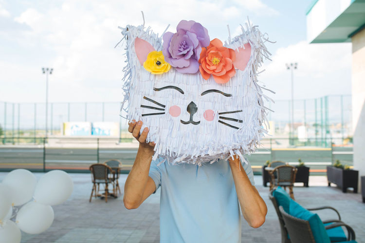 A guy holding cat pinata instead of his head