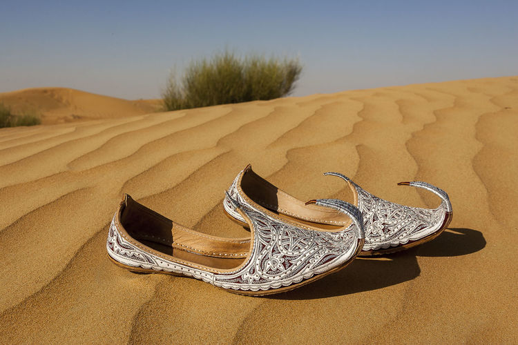 Close-up of footwear on sand in desert