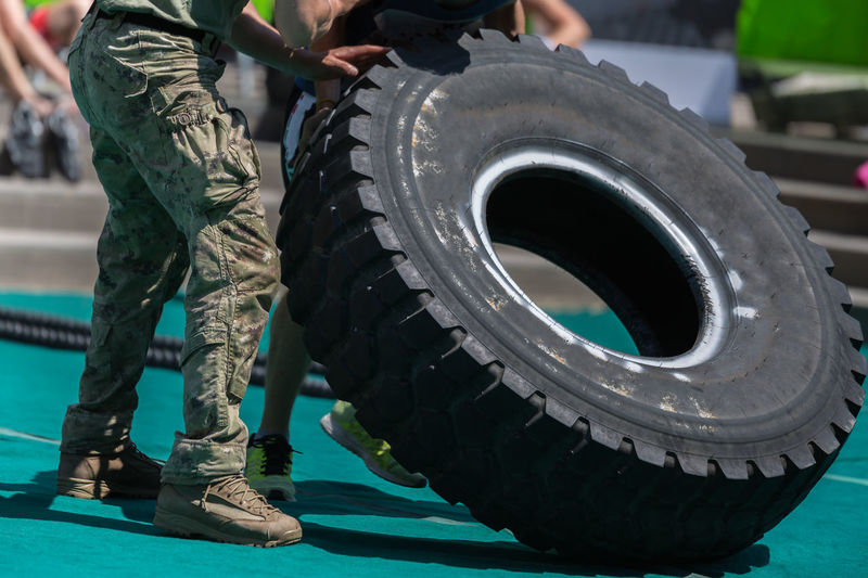 Low section of men carrying tire