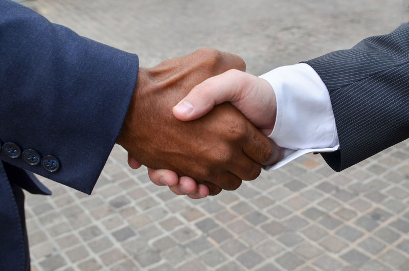Close-up of businessmen shaking hands at street
