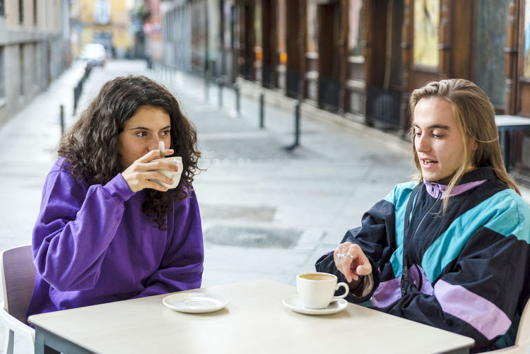 Portrait of young woman using mobile phone while sitting in cafe