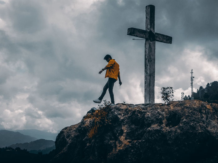 Man standing on cross against mountains against sky