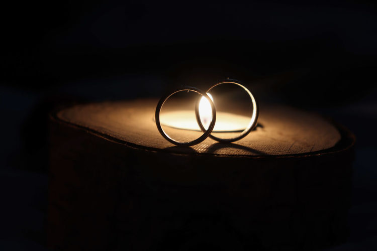 Close-up of rings by illuminated tea light on wood