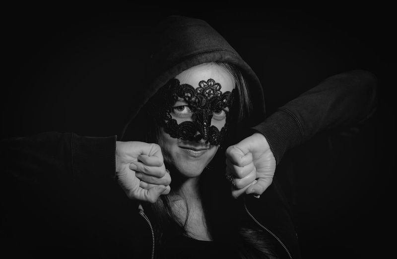 Portrait of woman wearing eye mask against black background
