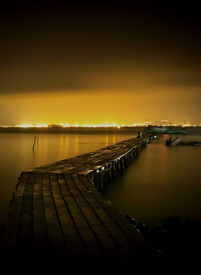 Pier over lake against sky during sunset