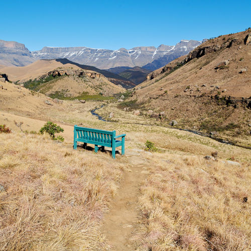 Information sign on field by mountains against clear blue sky