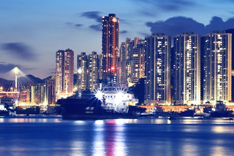 Illuminated modern buildings in city against sky at night
