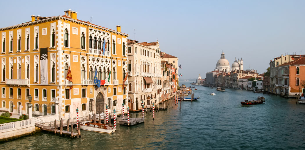 Boats in canal amidst buildings against sky