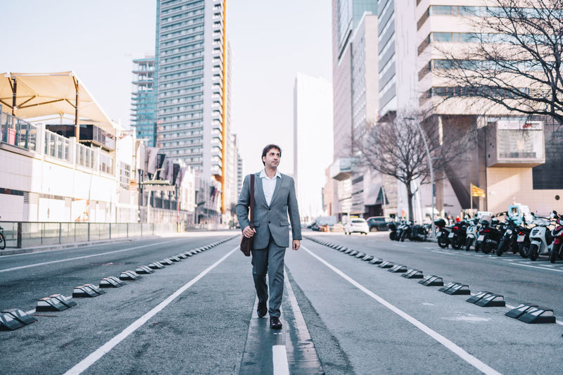Full length portrait of young man standing on road in city