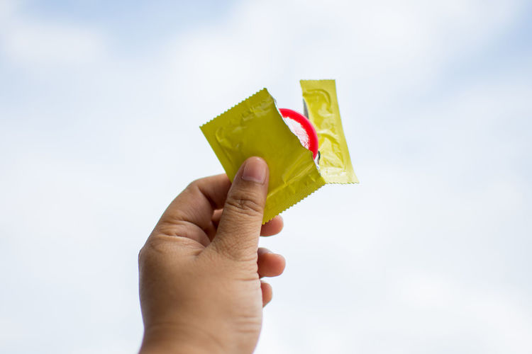 Close-up of man holding torn condom packet