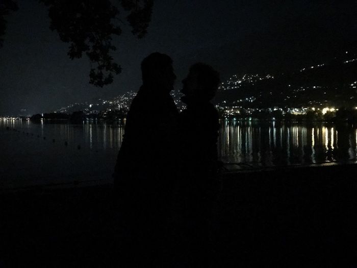 Silhouette couple standing against illuminated sky at night