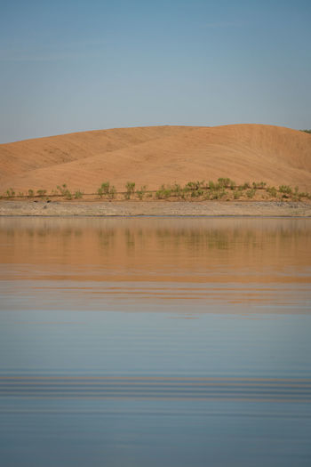 Desert like hill landscape with reflection on the water on a dam lake reservoir in terena, portugal