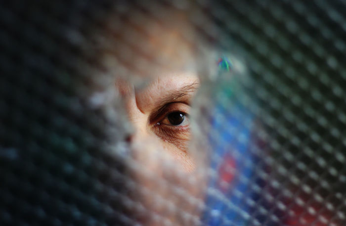Close-up portrait of woman looking through broken glass