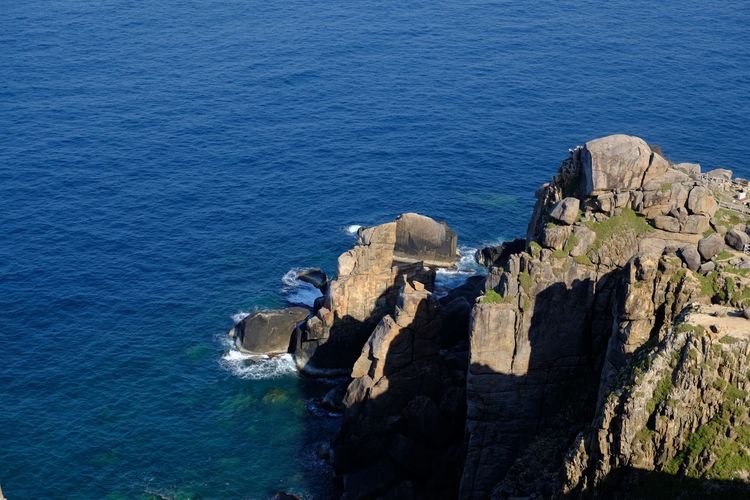 High angle view of rocks by sea against blue sky