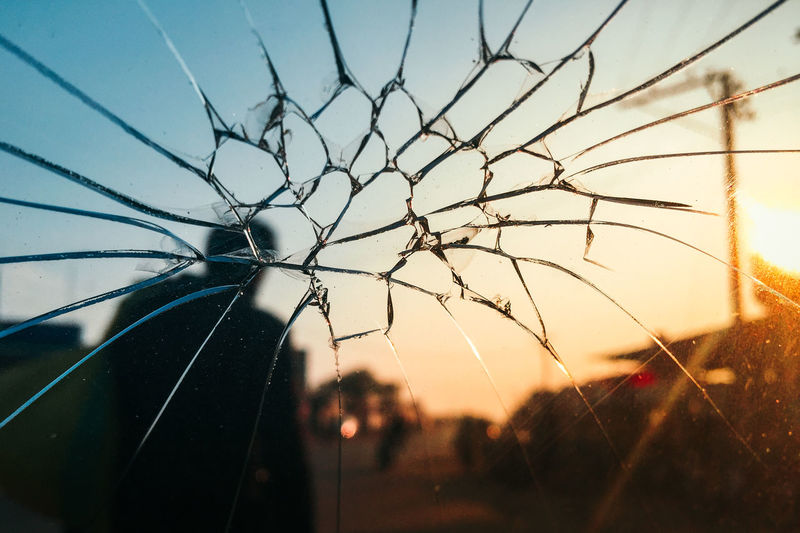 Close-up of cracked car windscreen against sky during sunset