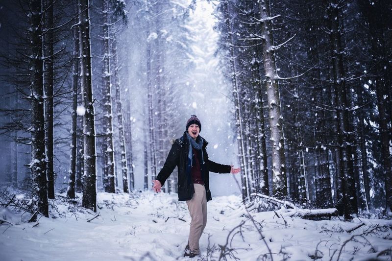Man standing on snow against bare trees