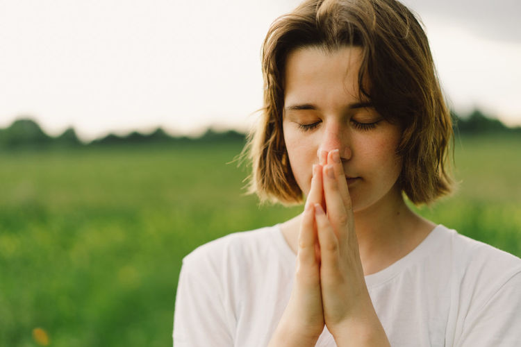 Teenager girl closed her eyes, praying. hands folded in prayer concept for faith