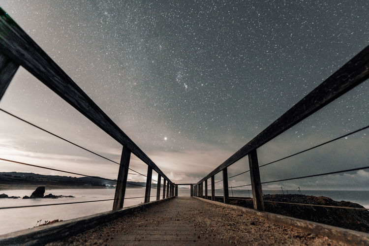 Bridge over sea against sky at night