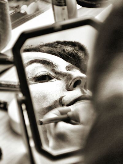 Reflection of woman applying make-up seen in mirror