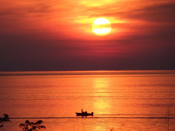Silhouette boat in lake erie against orange sky during sunset