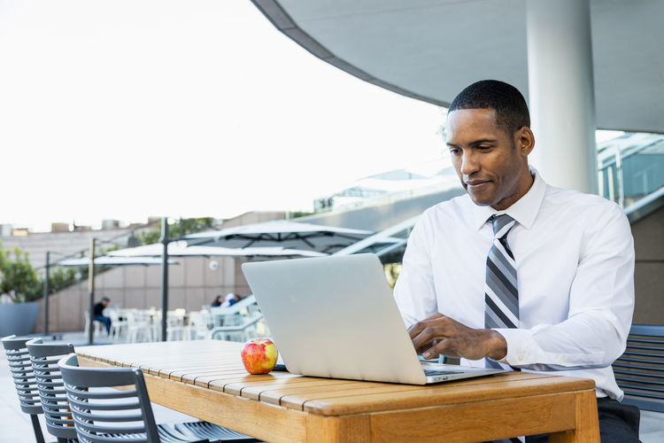 Portrait of businessman using laptop while sitting on table