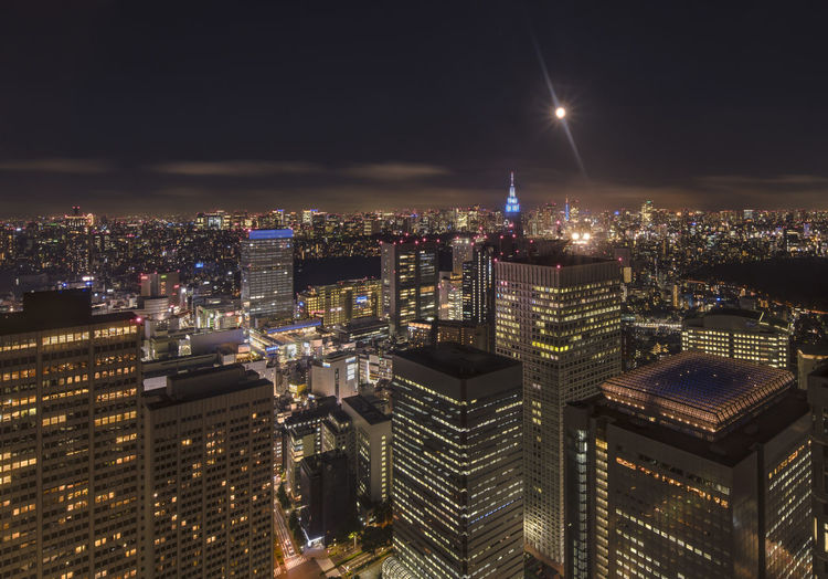 Illuminated cityscape of shinjuku  against full moon sky at night