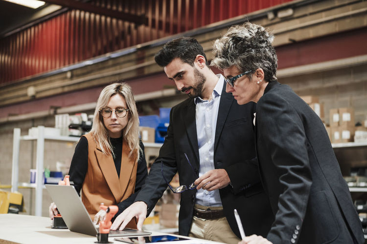 Businessman discussing with businesswomen over laptop at industry